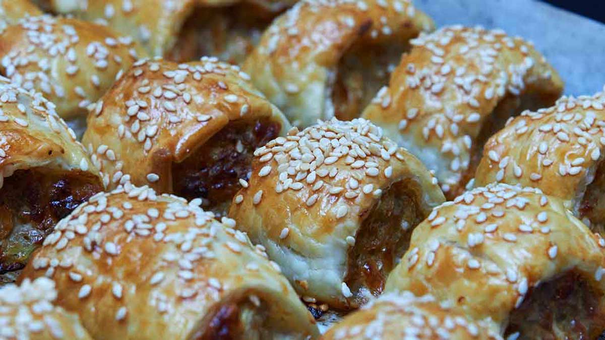 Cooked sausage rolls in three rows on a tray.