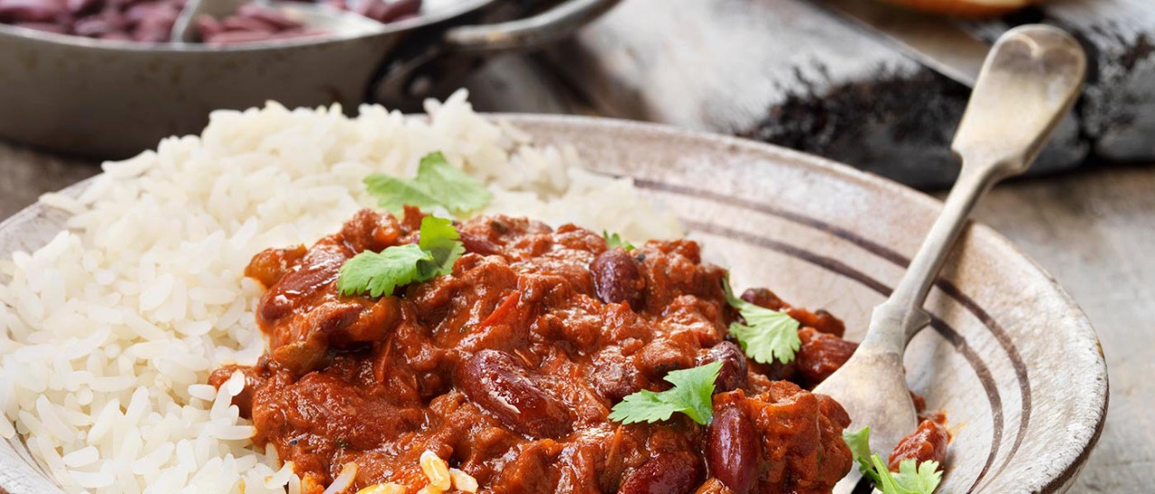 Kidney bean stew with white rice on plate with one fork.