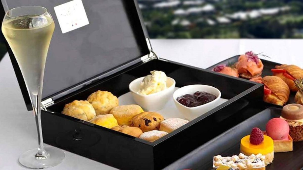 boxed jam and scones next to a glass of champagne and cakes