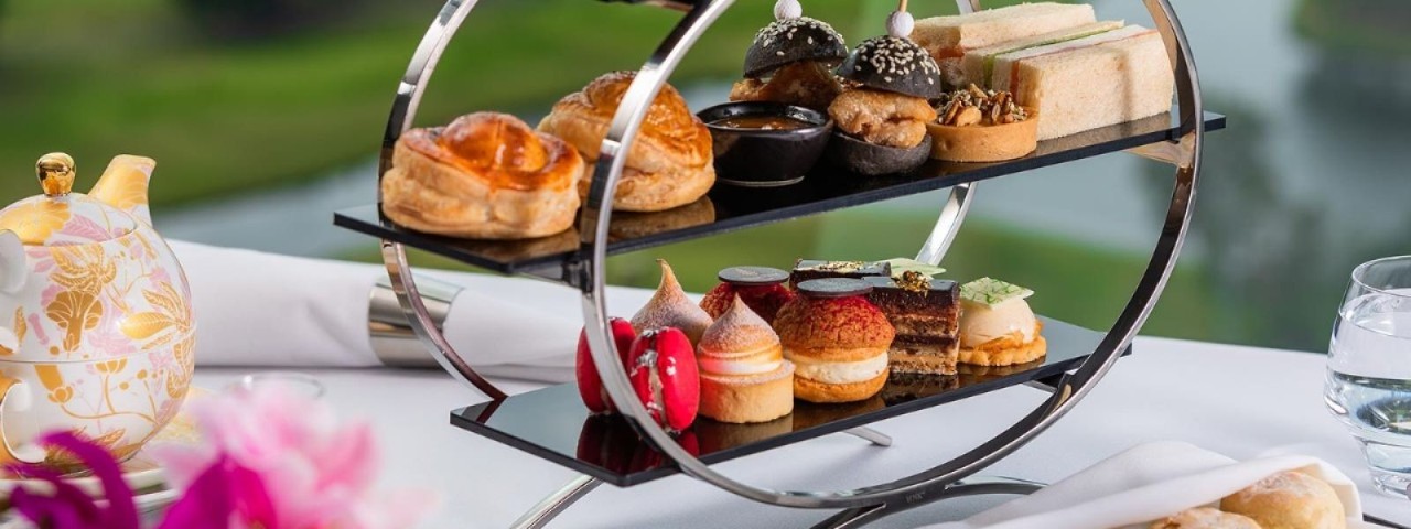 assortment of cakes and pastries on a table next to a teapot and flowers