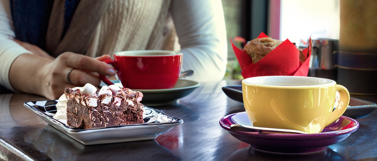Woman with cake and coffee in red cup in a cafe.