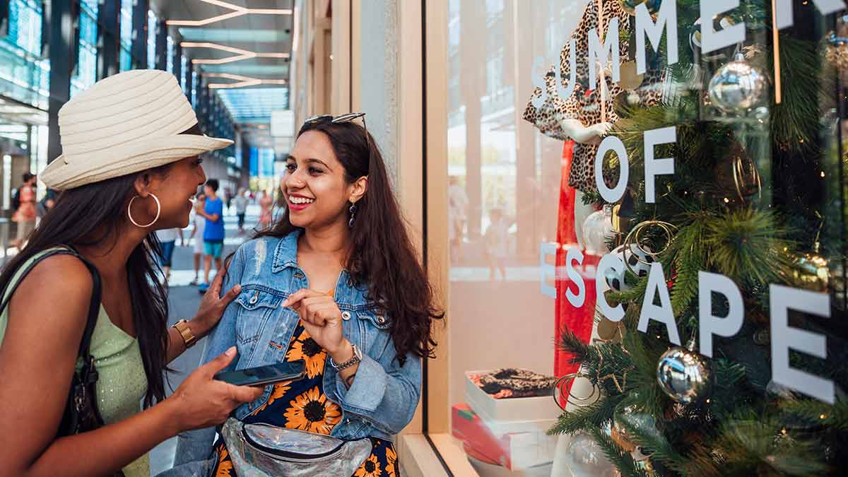 Two women chatting outside clothing store
