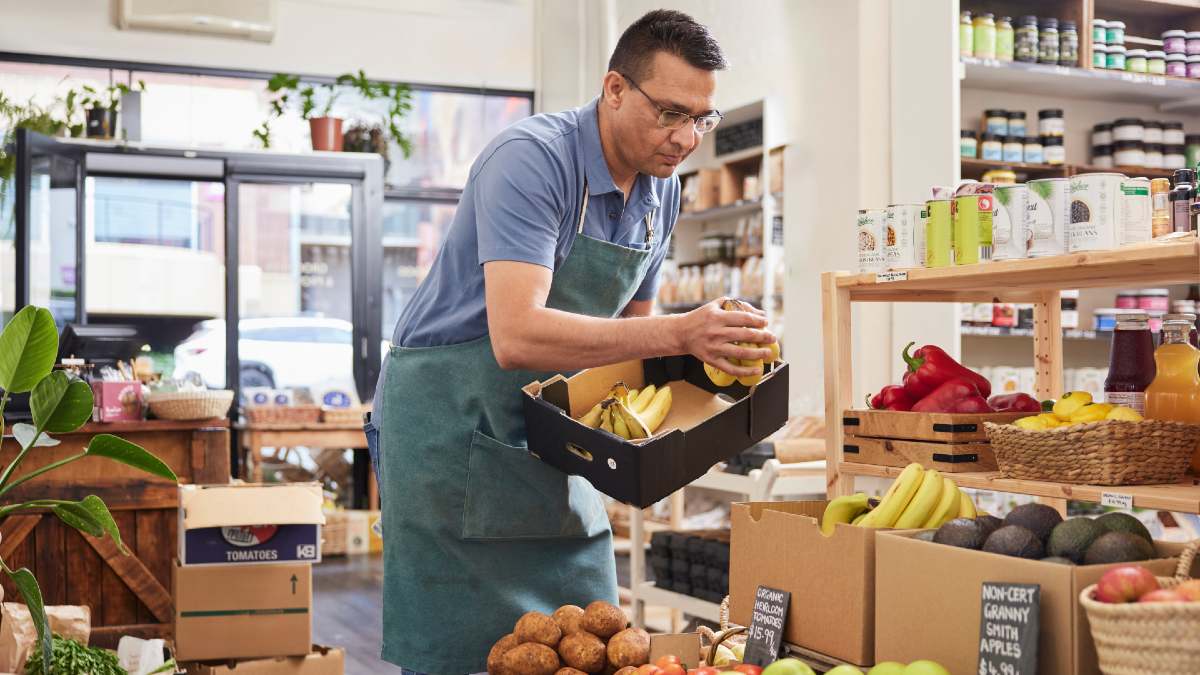 grocer stacking bananas in shop