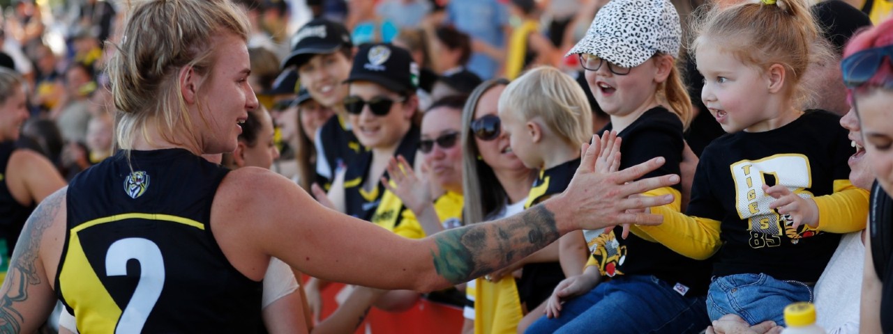 An AFLW player giving a high five to a young girl post-match