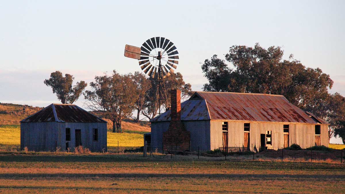 Two rural sheds and a wind turbine at sunrise