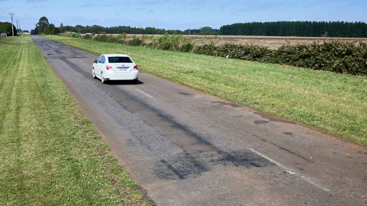 country road with unbalanced road sign on side of road