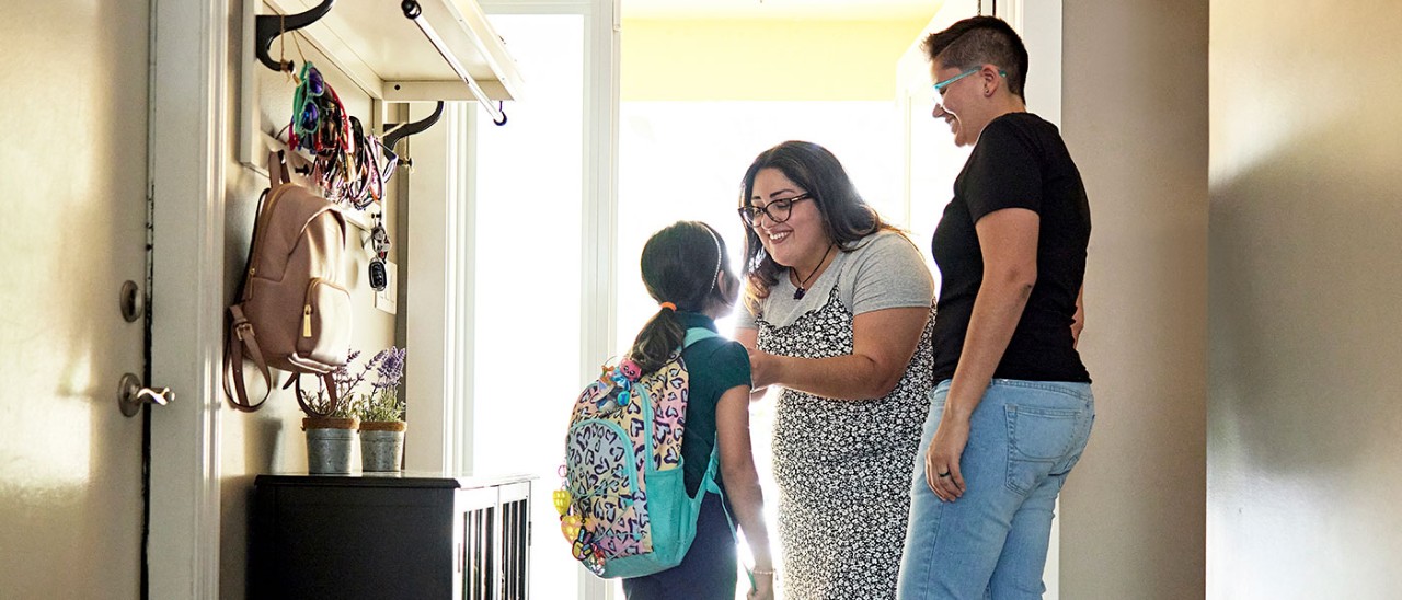A couple say goodbye to their daughter at the front door as she heads off to school.