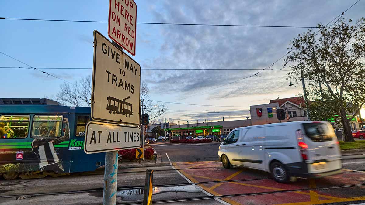 Van going through dangerous intersection past stationary tram