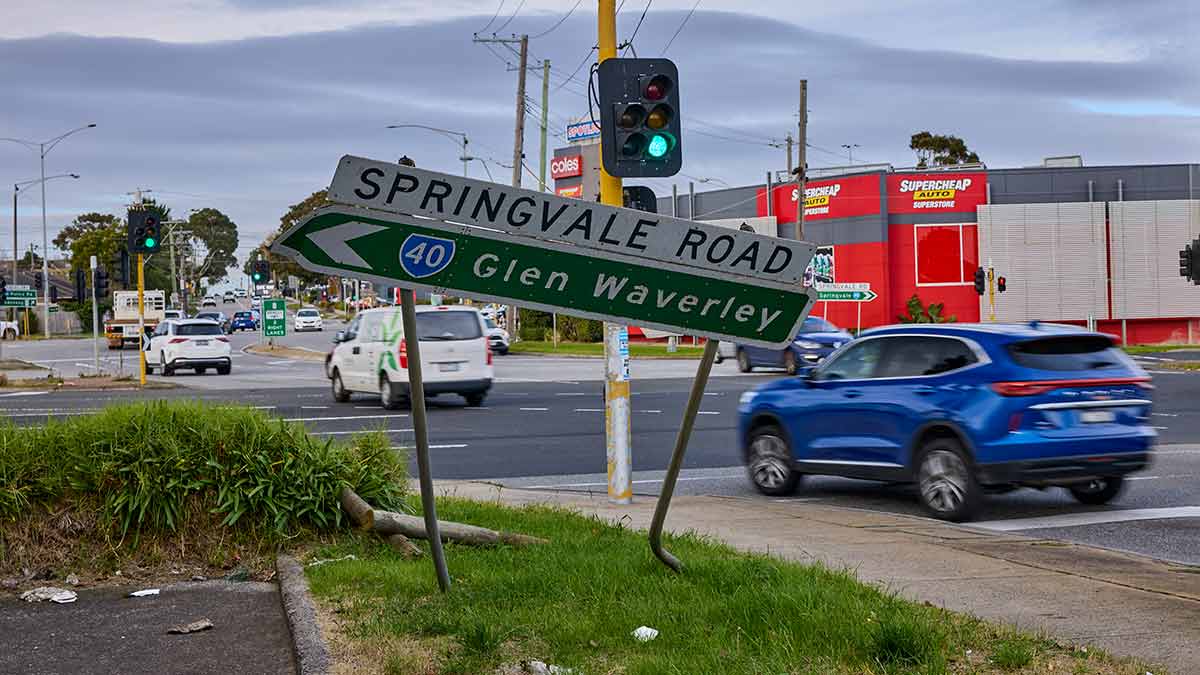 Cars going through intersection past bent road sign
