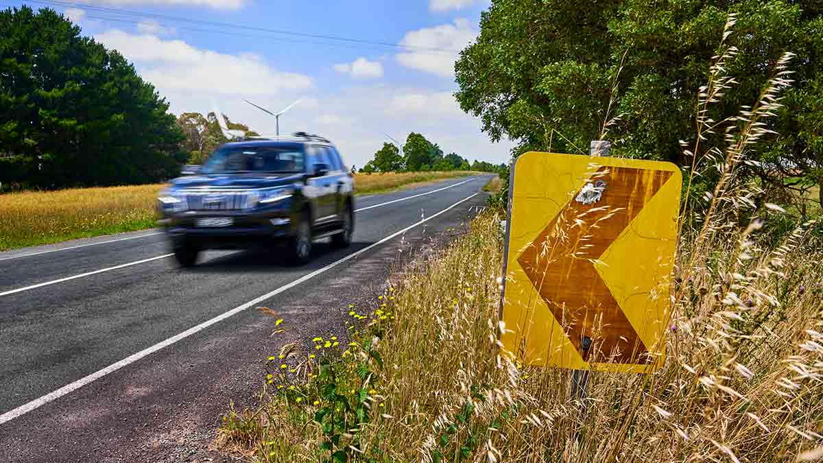 car travelling on country road passing faded arrow sign