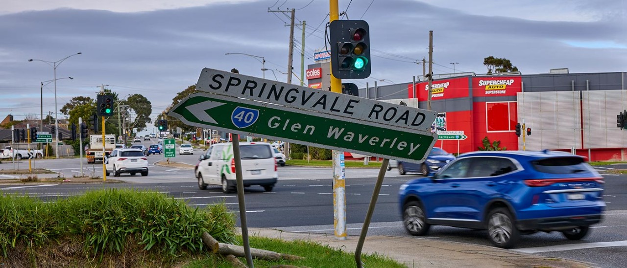 Princes-Hyw-Springvale-Rd-Mulgrave-0907-1400x600.jpg Car going through intersection past bent road sign