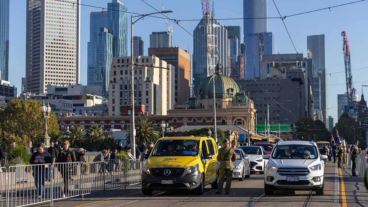 RACV van taking part in Anzac Day parade against backdrop of Melbourne's CBD.