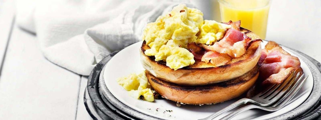 Bacon and eggs on muffins, served on a plate.