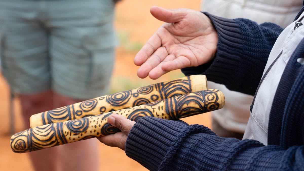A staff member holds clapsticks at a Yalari Outback Camp in Australia.