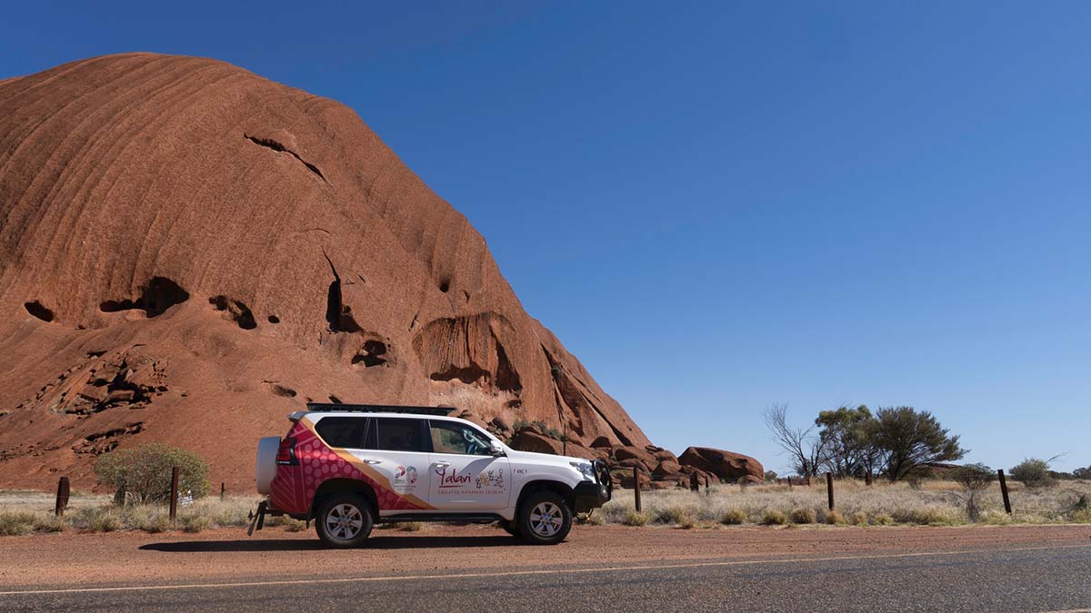 An SUV with a Yalari logo travels through Outback Australia