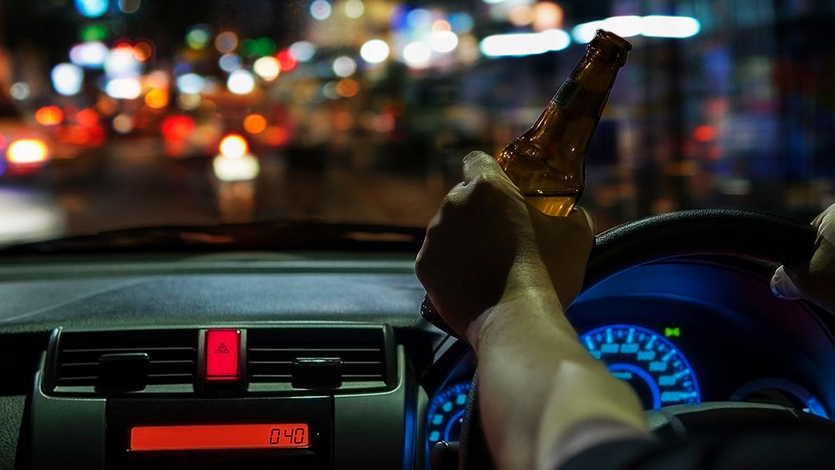Man driving with a bottle in his hand