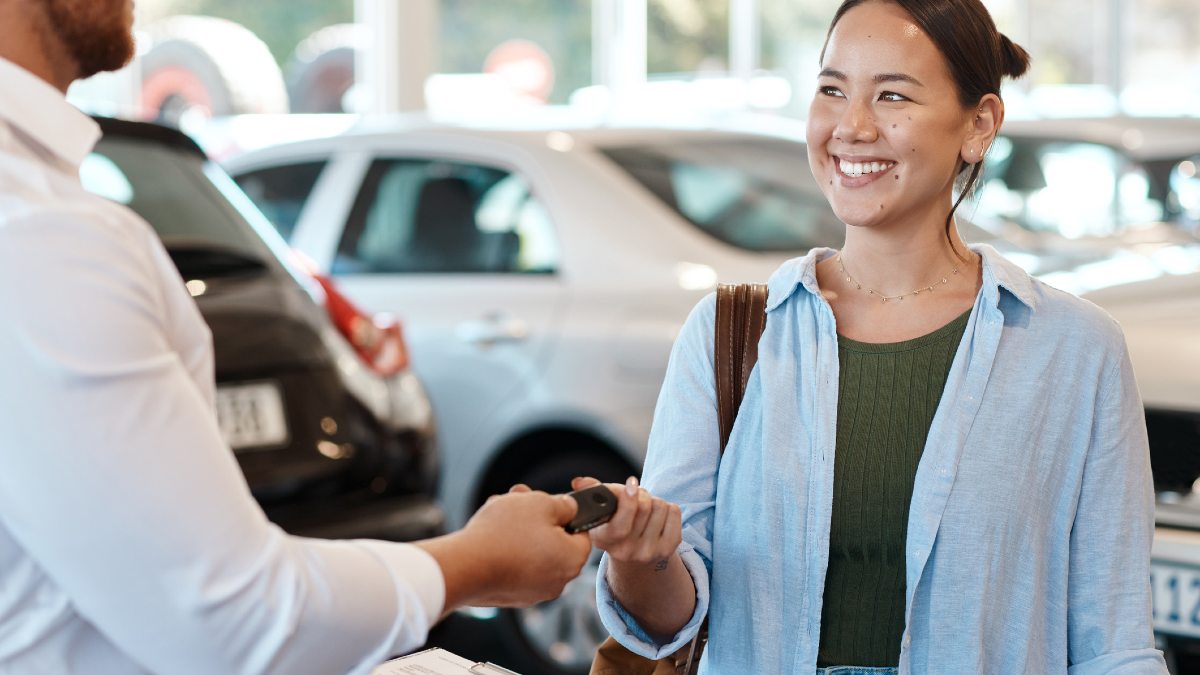 A woman being given car keys at a dealership