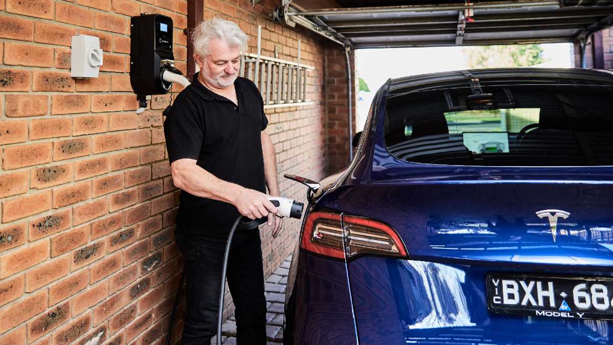 man plugging in EV at home