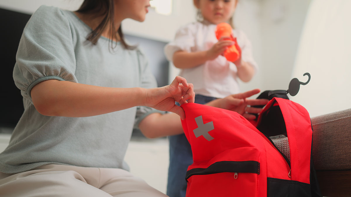 Mother packing home emergency pack with daughter watching