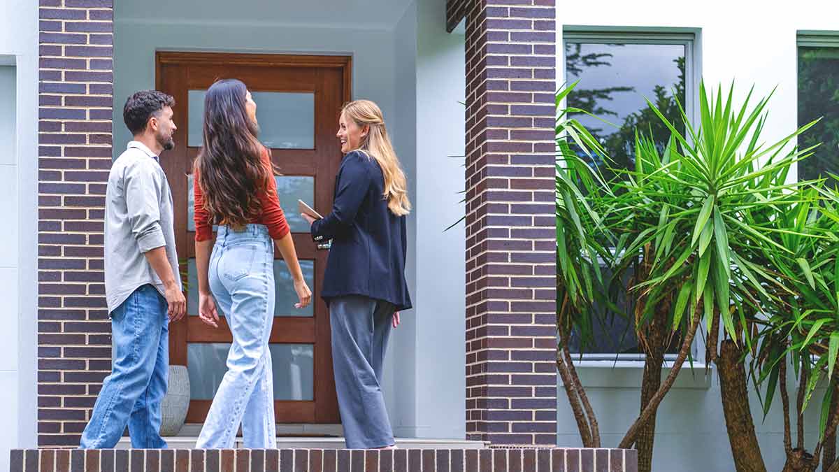 Couple with agent outside new home.
