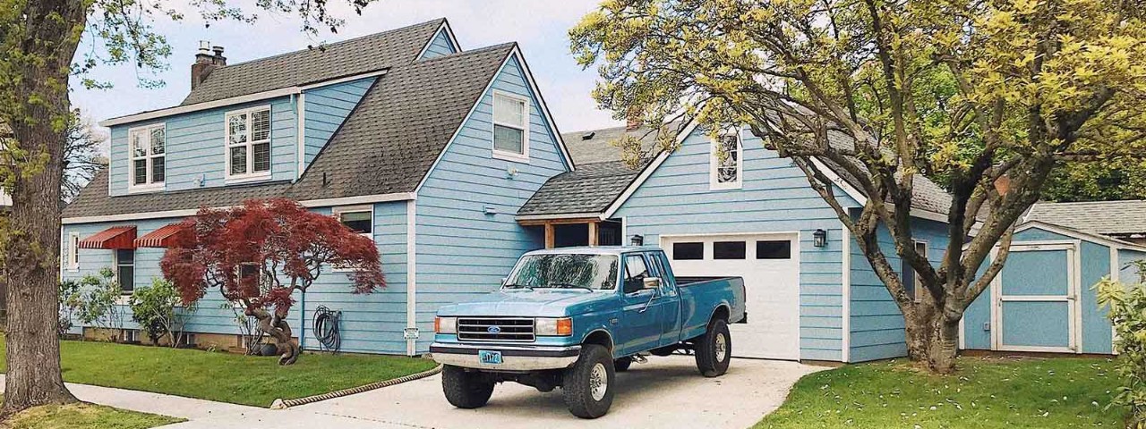blue ford vehicle parked in driveway of blue house