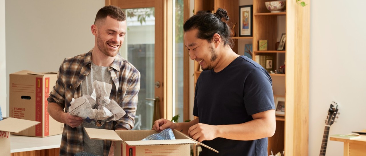 two young men unpacking in a new home