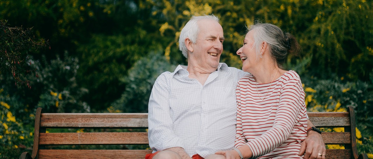 GettyImages-1418087070-1400x600.jpg senior couple sitting on bench smiling together