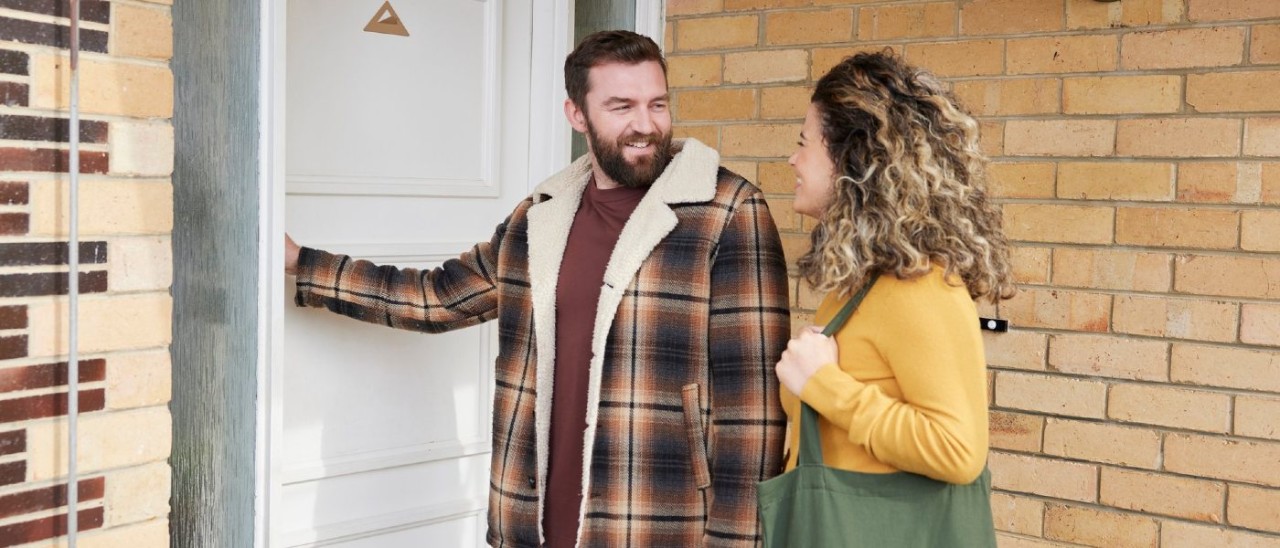 A man and woman happily about to enter a house through the front door