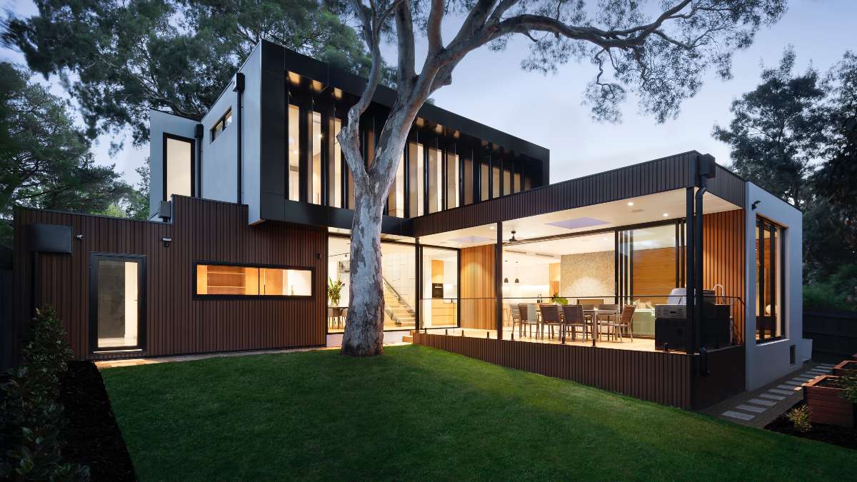outdoor view of two storey modern home with lights on and large outdoor area