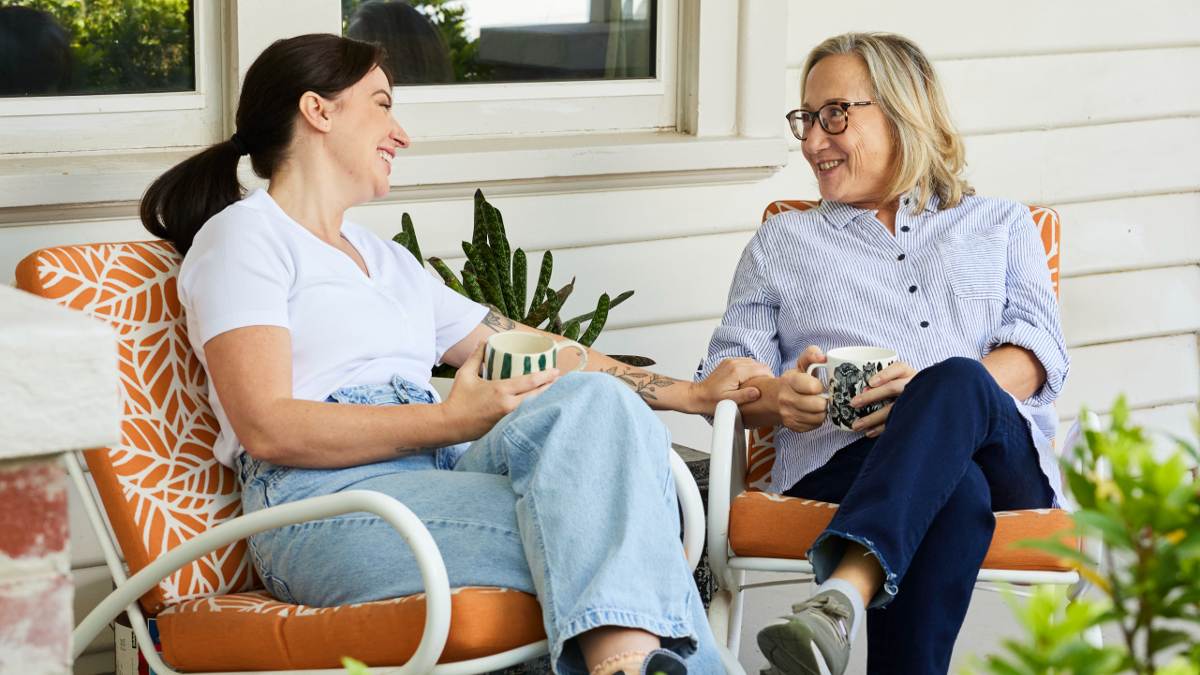 two women having a cup of tea together on porch