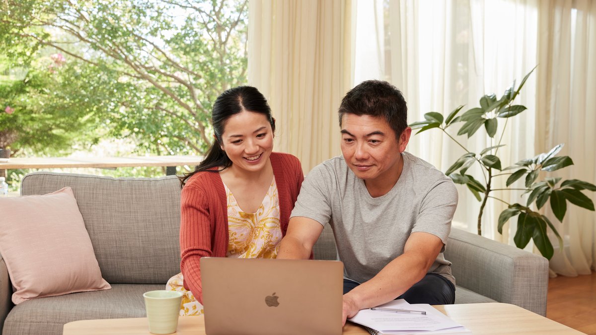 three people sitting at a table talking with paperwork and a laptop in front of them