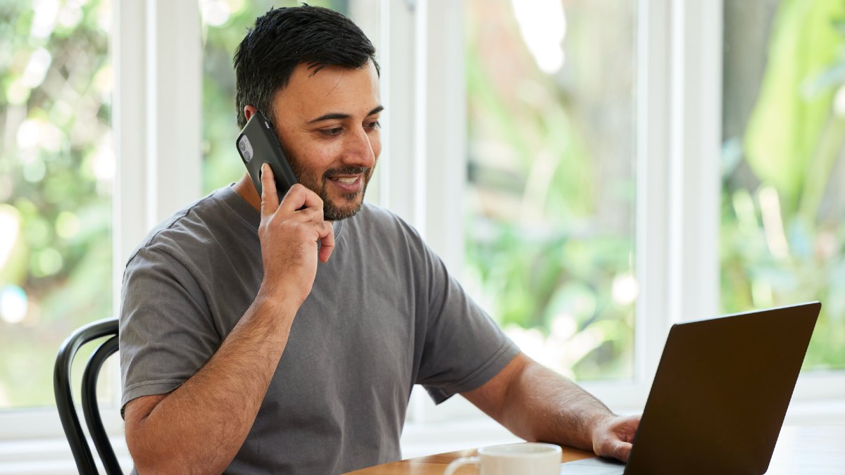 three people sitting at a table talking with paperwork and a laptop in front of them