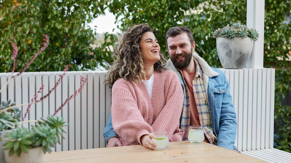 young couple on their veranda smiling with drinks