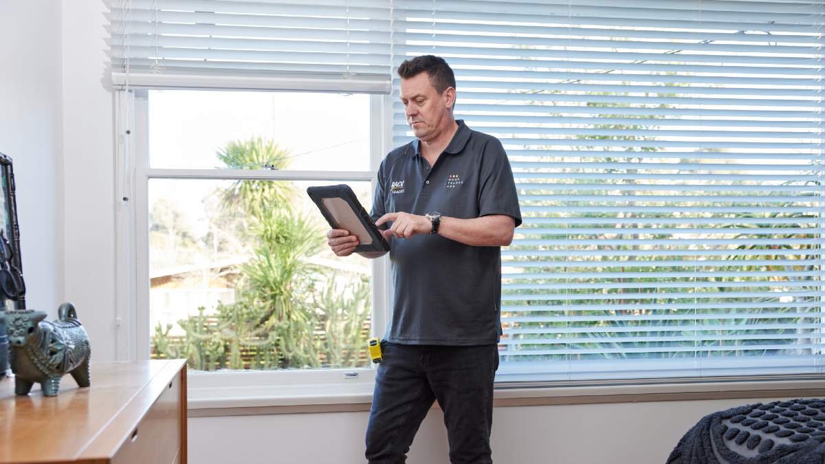 RACV tradie inspecting a home and typing his findings into a tablet