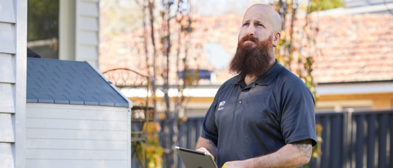 RACV home inspector typing on tablet outside a home