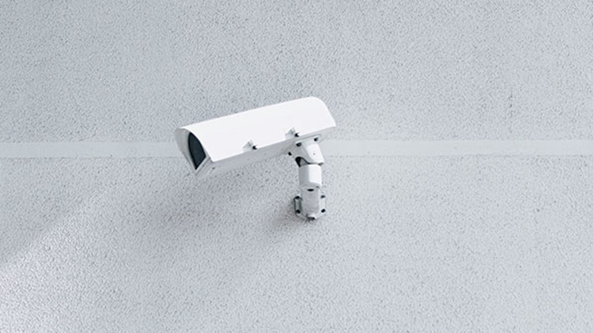 Security camera sitting upon a white wall.