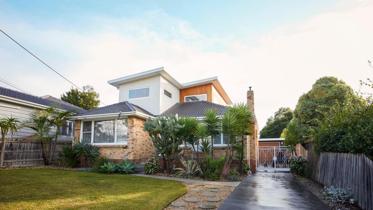 A two-storey suburban house. It is morning, and the grass and driveway in front of the house are still damp