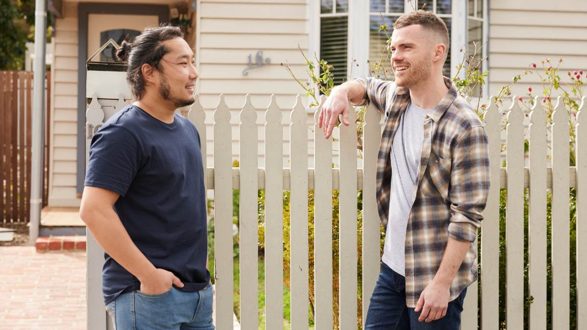 two young men talking at the fence out front of house