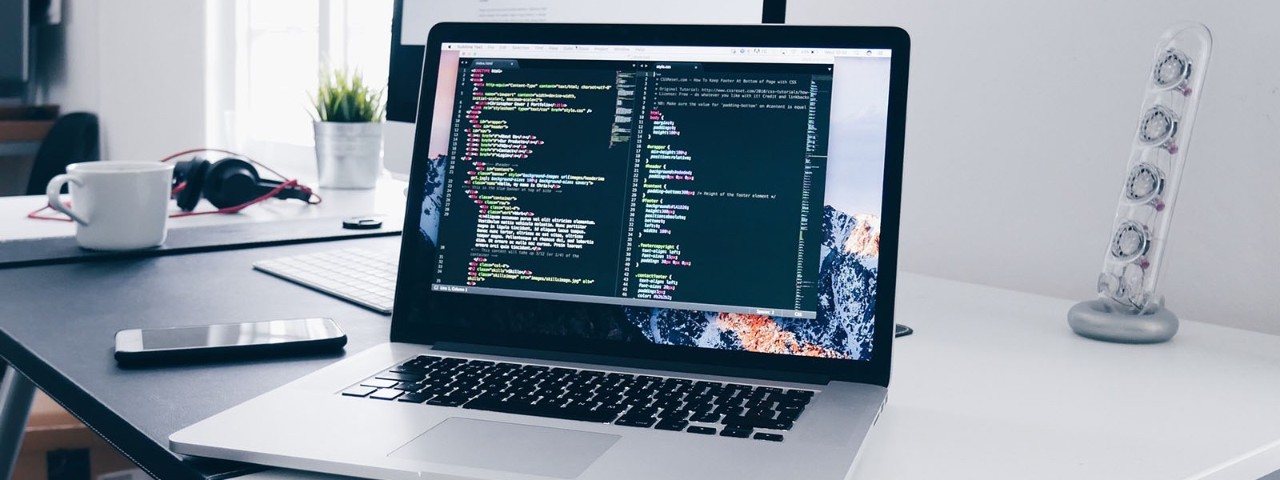 laptop on desk with coding on screen