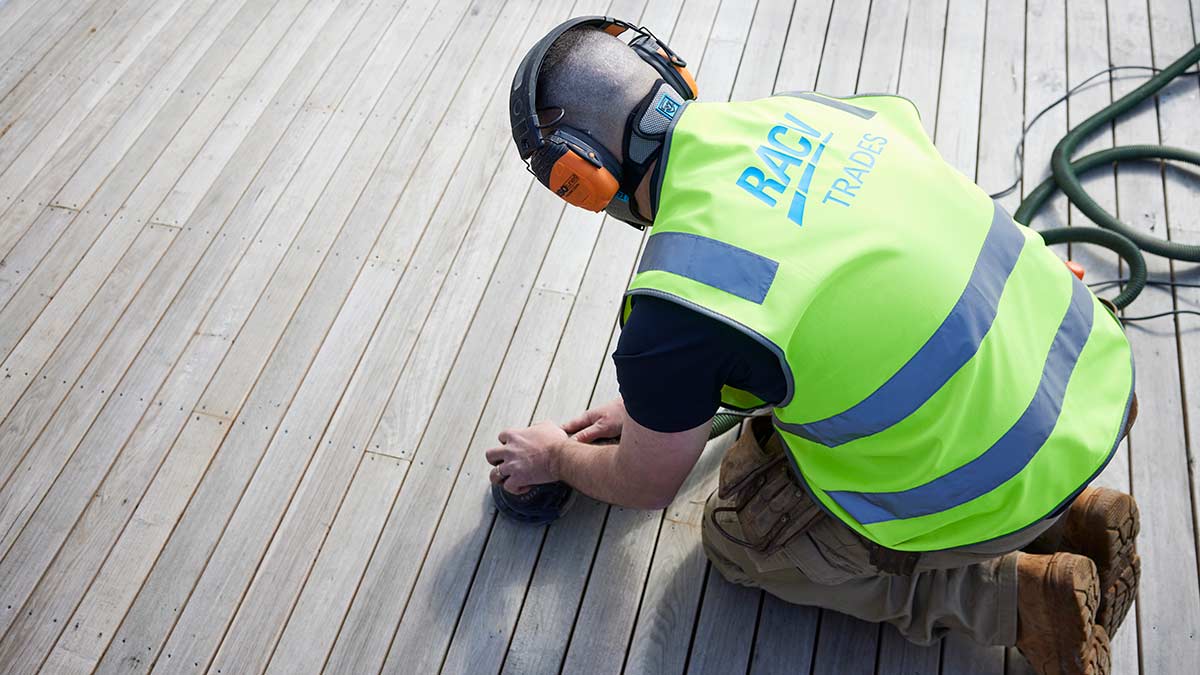 RACV Trades technician sanding down timber deck