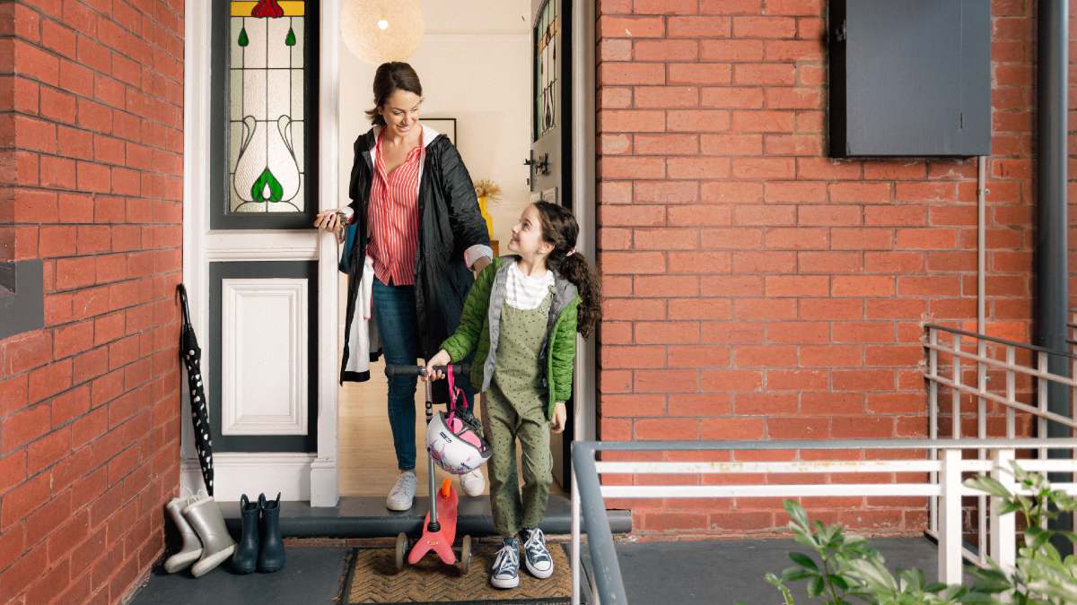 mother and daughter exiting their brick home in winter coats