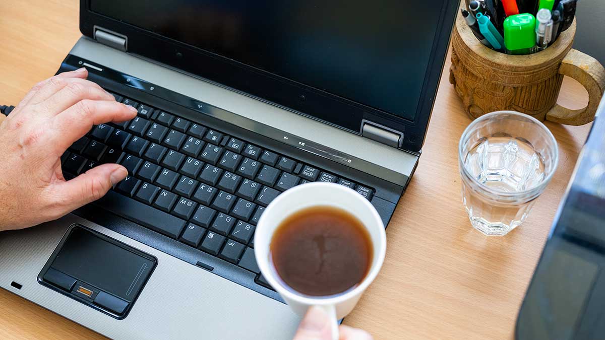 person working on computer drinking coffee