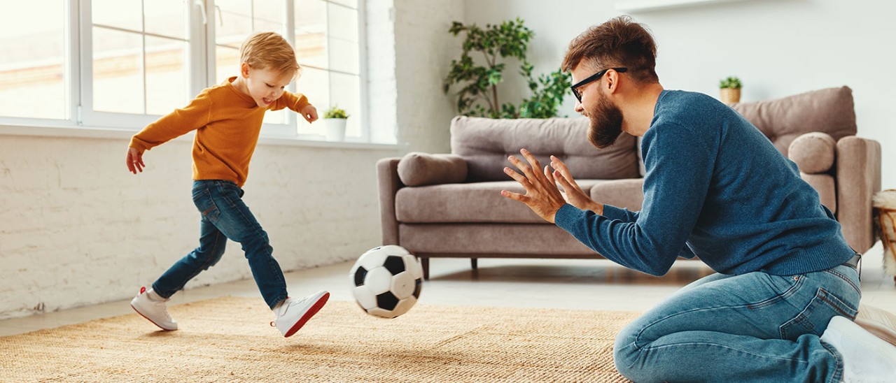 family-ball-insurance-getty-1224436250-1400x600.jpg boy kicking ball to father inside home