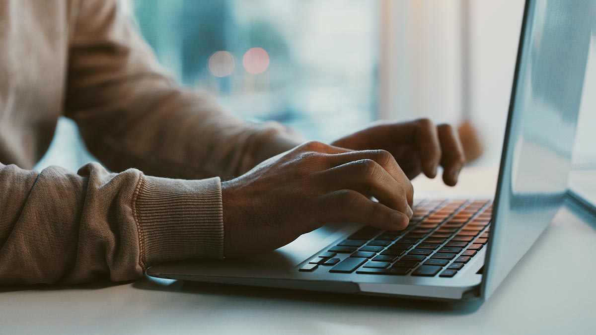 close-up of man's hands on laptop keyboard