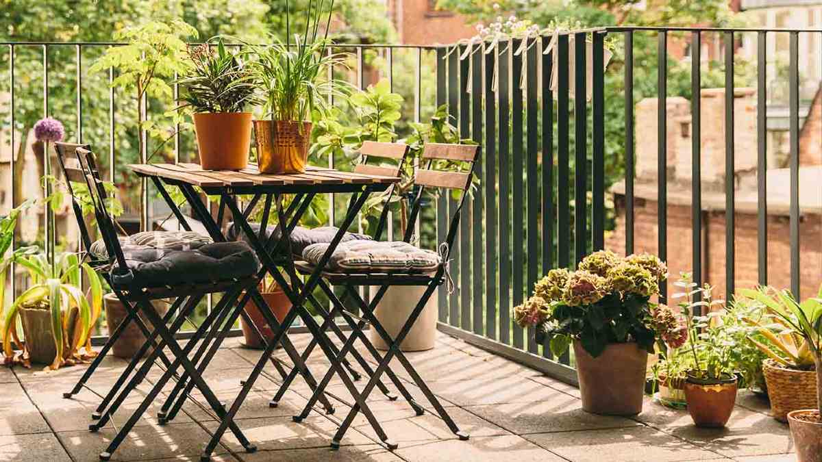 tables and chairs on a balcony surrounded by plants