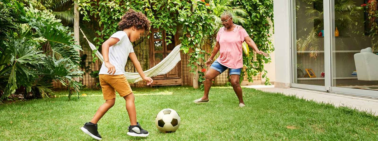 1249349866 grandma and grandson playing soccer on the grass lawn