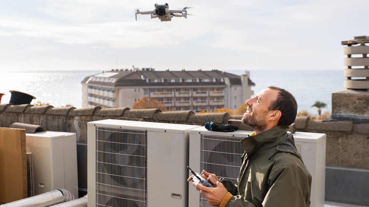 man watching drone in flight over buildings