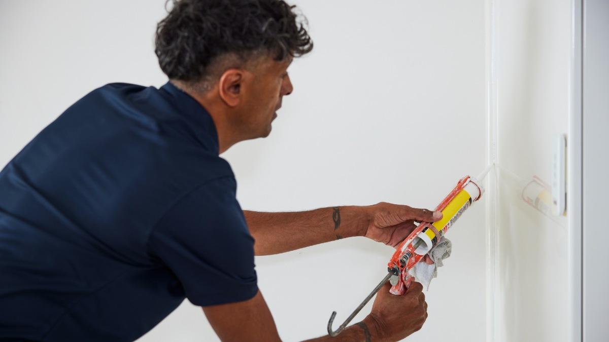 RACV tradie caulking a door
