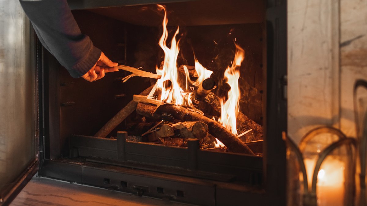person placing a stick on an indoor fireplace