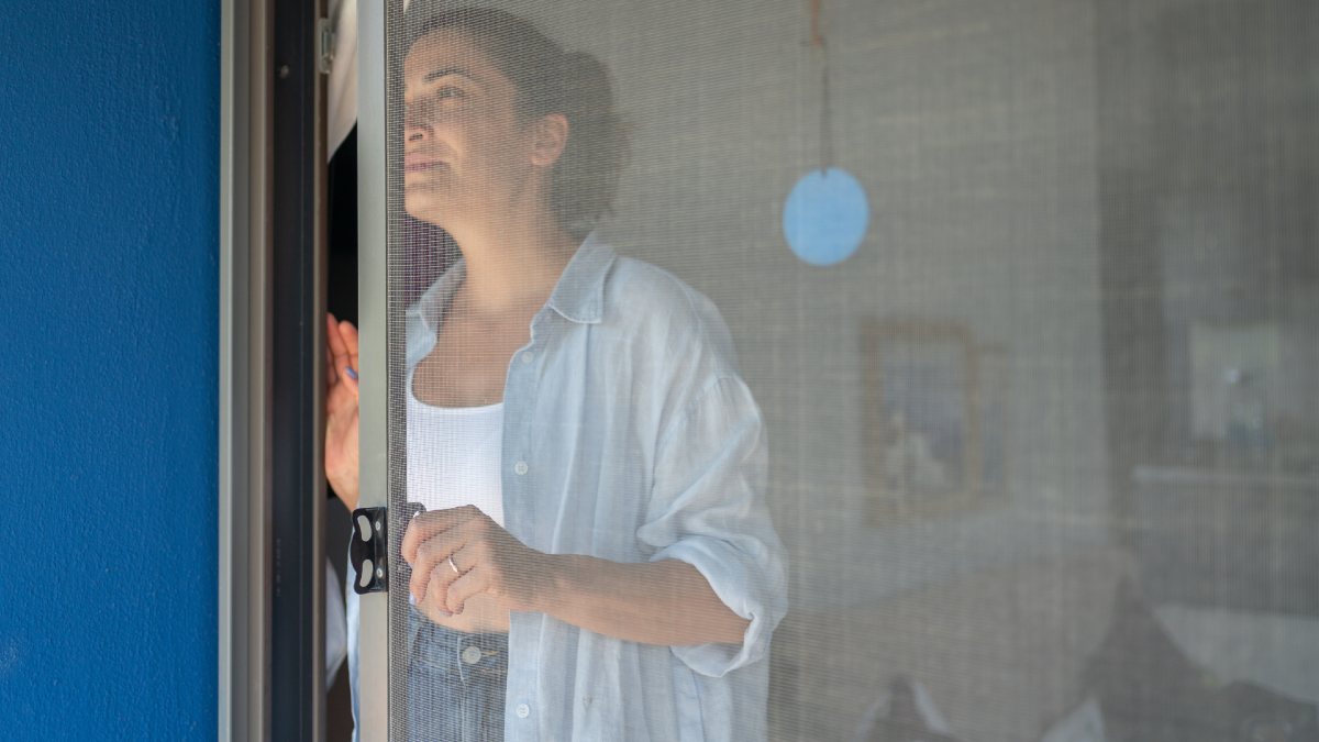 woman closing a mosquito-proof screen door to her home